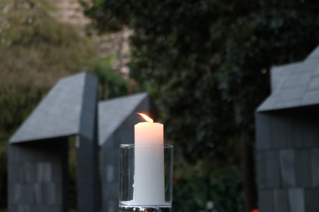 Lit candle with police memorial in the background. 