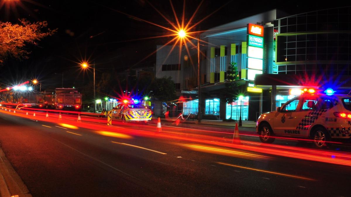 Police cars driving at night with flashing lights on. 