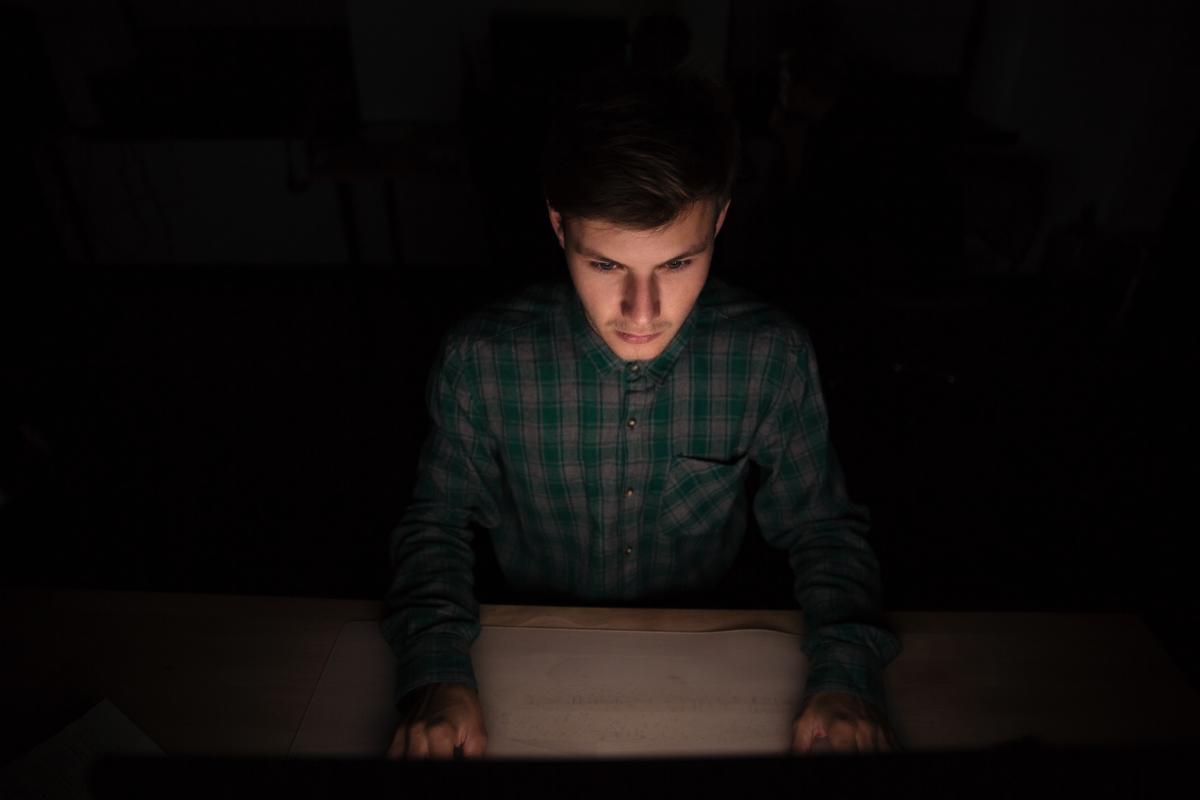 generic images of young man using computer in dark room